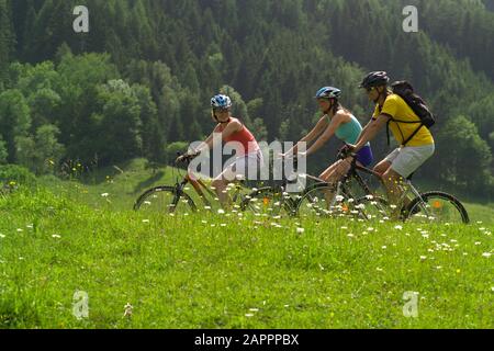 Junge Leute beim Radfahren durch Österreichische Landschaft bei Schladming - Österreichisches Landratsseite bei Schladming, Freunde Radeln Stockfoto