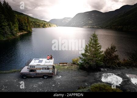 Freunde, die einen Blick auf den See auf Campervan, Cathedral Grove, British Columbia, Kanada genießen Stockfoto