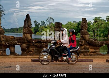 Menschen auf dem Motorrad auf Brücke mit Skulpturen, die zu Giant Gopuram, Südtor, Angkor Thom, Angkor Wat, Unesco-Weltkulturerbe führen Stockfoto