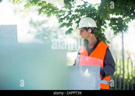 Frau, die im Freien in einer hohen Vis Jacke und einem sicheren Schutzhut arbeitet. Stockfoto