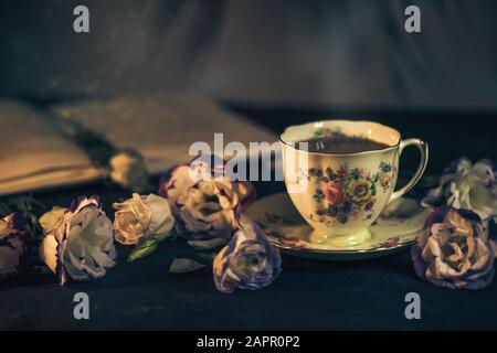 Stillleben mit einer Vintage-Tasse Tee, Buch und Blumen Stockfoto