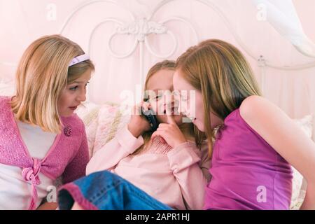 Ansicht von drei niedlichen Mädchen sprechen auf einem Telefon. Stockfoto