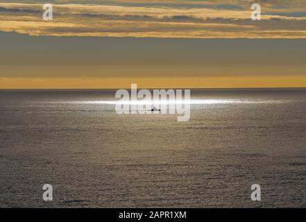 Ein einflücherndes Fischerboot an einem Sonnenblender, der auf das Dorset-Meer scheint Stockfoto