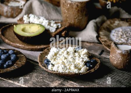 Gesundes Frühstück. Verschiedene Frühstücksküche mit gerountem Weizen, Joghurt, Kefir, Hüttenkäse, Avocado, Roggenbrot, Samen, Nüssen und Beeren Sortiment i Stockfoto