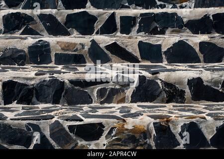 Steintreppe auf der Straße aus schwarzen Steinen und grauem Zement. Stockfoto