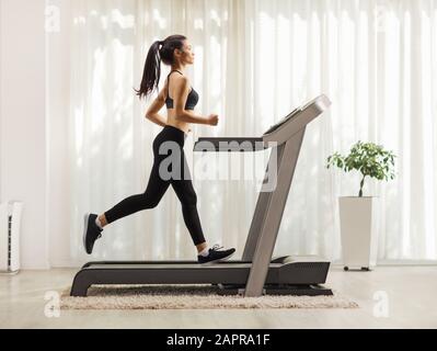 Profilaufnahme in voller Länge von jungen Frauen, die auf einem Laufband in Innenräumen laufen Stockfoto