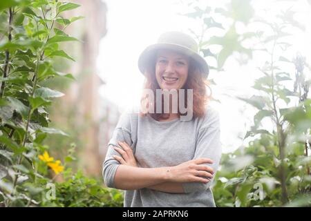 Junge Frau draußen in einem städtischen Garten mit Hut Stockfoto