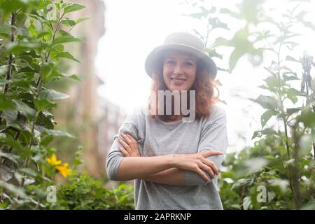 Junge Frau mit Sommerhut draußen in einem städtischen Garten Stockfoto