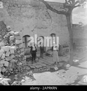 Israel 1948-1949: Peki'in Dorfbewohner vor dem Eingang zu einer Synagoge Anmerkung: Der Tradition nach wurden 2 Steine beim Bau dieser Synagoge aus den Wänden des alten jüdischen Tempels in Jerusalem aus der Römerzeit verwendet Datum: 1948 Ort: Galiläa, Israel, Peki'in Schlüsselwörter: Fassaden, Straßenskulpturen, Synagogenbauten Stockfoto