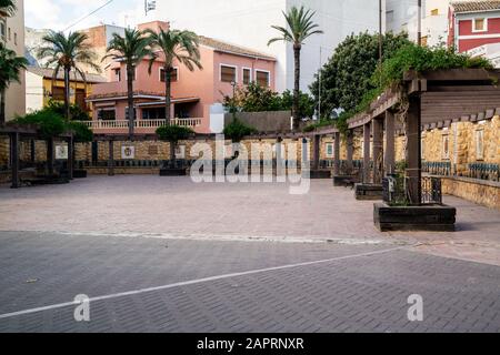 Schöne Aussicht auf eine Straße in Polop, Spanien, umgeben von Babassu Palmen und bunten Gebäuden Stockfoto