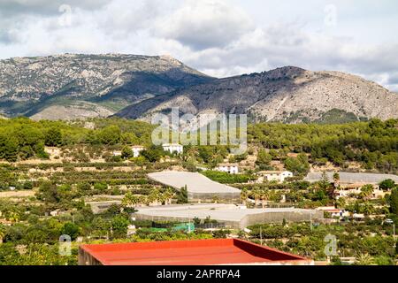 Landschaftsaufnahme der Gebäude und Natur von Polop Stadt, Spanien mit Bergen im Hintergrund Stockfoto