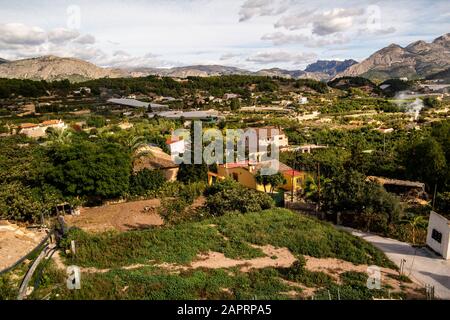 Vogelperspektive auf die üppige Natur und alte Gebäude mit wunderschönen Bergen in Polop, Spanien Stockfoto