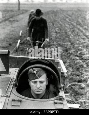 Spaarnestad Foto/SFA02804386 Zweiter Weltkrieg Deutscher Soldat im Panzerkuppel der Tankette. Die hinter ihnen stehenden französischen Bauern bekommen Hilfe von deutschen Soldaten beim Pflügen des Landes. Frankreich, 1941. [Möglicherweise ein Renault UE aus Frankreich: Ein gepanzerter Traktor, von den Deutschen modifiziert und benutzt]. Zweiter Weltkrieg. Deutscher Soldat in einem Panzer. [Möglich ein Renault UE, ein französisches Fahrzeug für armorierte Traktoren oder Infanteriezulieferer, entwickelt für Versorgungsarbeiten, die von den Deutschen verwendet und modifiziert werden]. Deutsche Soldaten helfen den französischen Bauern, ihre Felder zu pflügen. Frankreich, 1941; Stockfoto