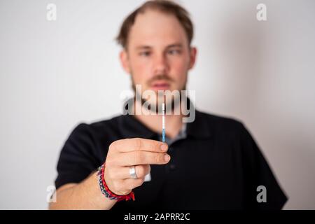 Positiven Schwangerschaftstest, gehalten von einem überrascht Mann im Hintergrund Stockfoto