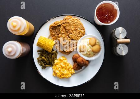 Schweinekotelteller mit Seiten und süßem Tee auf schwarzer Tischplatte Stockfoto