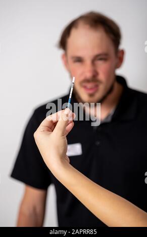 Positiven Schwangerschaftstest, gehalten von einem überrascht Mann im Hintergrund Stockfoto