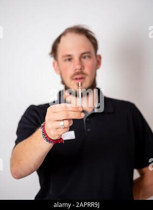 Positiven Schwangerschaftstest, gehalten von einem überrascht Mann im Hintergrund Stockfoto