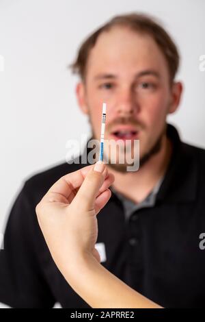 Positiven Schwangerschaftstest, gehalten von einem überrascht Mann im Hintergrund Stockfoto