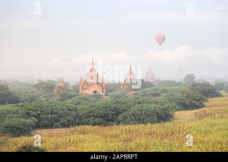 Heißluftballon, der bei Sonnenaufgang in Bagan über alten Tempeln fliegt Stockfoto