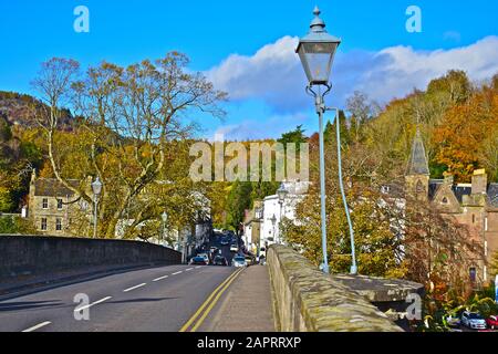 Ein wunderbarer Blick von der Brücke über den Fluss Tay in Dunkeld, der die Hangbäume in ihren schönen Herbstfarben Grün, Gold und Braun zeigt. Stockfoto