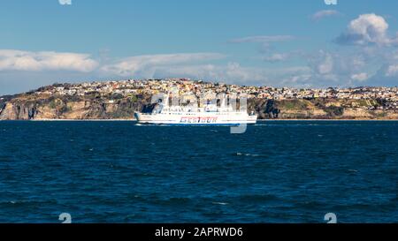 Procida, ITALIEN - 5. JANUAR 2020 - Insel Procida, ein Fährschiff und ein Blick auf den Monte di Procida an einem sonnigen Tag im Winter Stockfoto