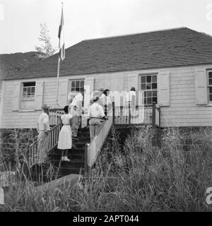 Niederländische Antillen und Suriname zum Zeitpunkt des königlichen Besuchs von Königin Juliana und Prinz Bernhard im Jahr 1955 Wird Eine alte Frau in einem Stuhl in das Haus auf Saba getragen, wo der Empfang des Königspaares stattfinden wird Datum: 27. Oktober 1955 Ort: Niederländische Antillen, Saba Schlüsselwörter: Ältere Menschen, Gebäude, Straßenbilder Stockfoto