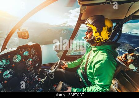 Hubschrauberpilot. Hubschrauber fliegen Flugzeuge über Berge und Meer. Sonniger Tag. Blick aus dem Inneren des Hubschraubers. Stockfoto