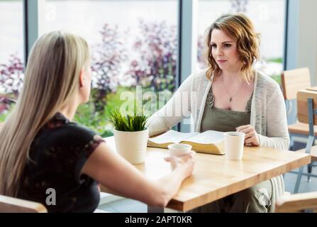 Zwei Kollegen diskutieren, was sie gelernt haben, nachdem sie gemeinsam in einem Kirchencafe ein Bibelstudium gemacht haben: Edmonton, Alberta, Kanada Stockfoto