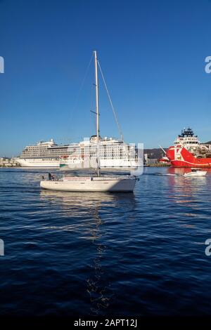 Segelboot Erster Spieler. Im Hintergrund fährt das Kreuzfahrtschiff Viking Star am Skolten Kai im Hafen von Bergen, Norwegen. Tankschiff Oslo Tank neben dem großen c Stockfoto