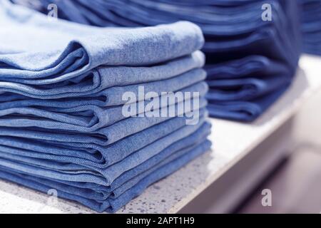 Stapel blauer Jeanshosen auf einem Regal im Geschäft Stockfoto