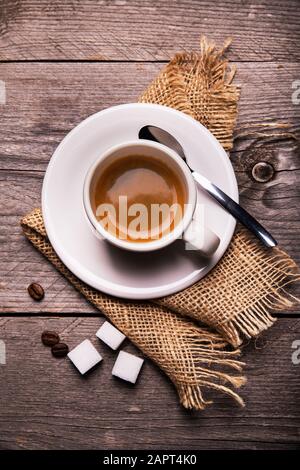 Auf dem rustikalen Holztisch, im Vordergrund, mit Blick von oben, eine Tasse cremigen Espresso-Kaffee. Vertikale Zusammensetzung Stockfoto