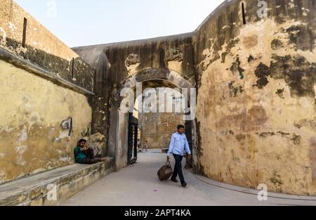 DIU, Indien - Dezember 2018: Ein Mann zieht sein Gepäck vor dem Eingangsbogen des Torways zum alten portugiesischen Diu Fort. Stockfoto