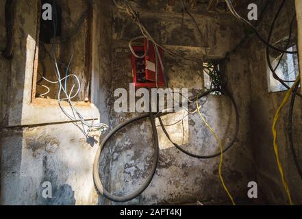 DIU, Indien - Dezember 2018: Elektrische Drähte und Kabel in einer kleinen, alten Kabine mit elektrischen Einheiten zur Übertragung von Elektrizität innerhalb des Diu Forts. Stockfoto