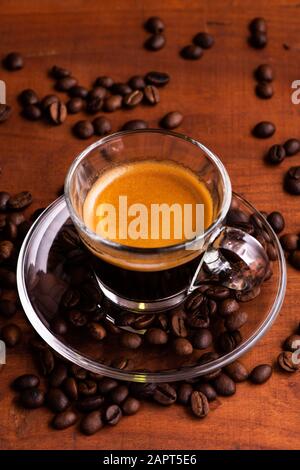 In Nahaufnahme cremiger Espresso in kleiner Tasse aus Glas auf Holztisch Stockfoto
