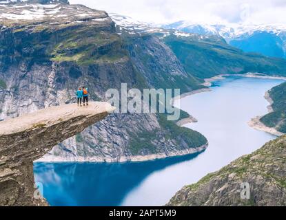 Paar posiert auf Trolltunga. Froh, dass Frau und Mann schönen See und gutes Wetter in Norwegen genießen. Stockfoto