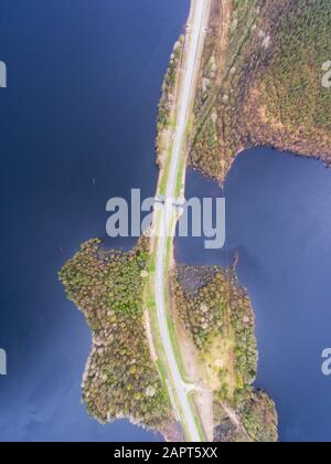 Schöner Blick von einer Straße durch den schönen See und Wald, auf beiden Seiten mit Wasser umgeben, oben von Drohne, luftige leuchtende Pic Stockfoto