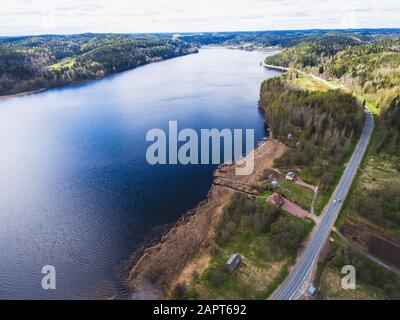 Schöner Blick von einer Straße durch den schönen See und Wald, auf beiden Seiten mit Wasser umgeben, oben von Drohne, luftige leuchtende Pic Stockfoto