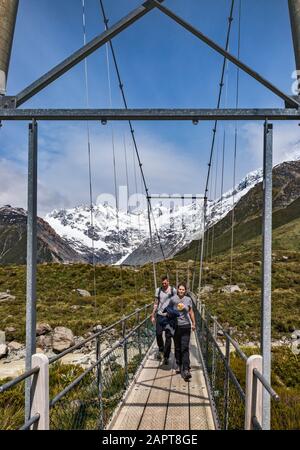 Wanderer auf der Drehbrücke am Hooker Valley Track, in der Nähe von Hooker Lake, Südalpen, Aoraki Mount Cook National Park, Canterbury, South Island, Neuseeland Stockfoto