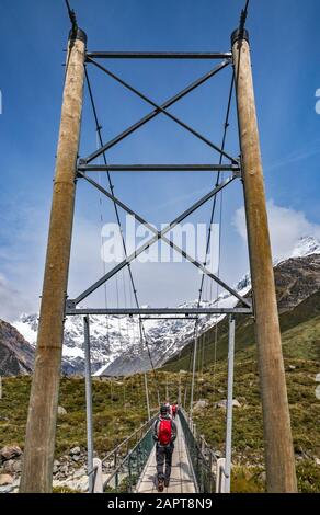 Wanderer auf der Drehbrücke am Hooker Valley Track, in der Nähe von Hooker Lake, Südalpen, Aoraki Mount Cook National Park, Canterbury, South Island, Neuseeland Stockfoto