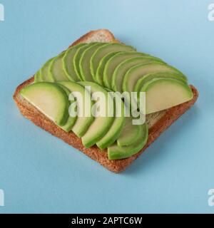 Toast mit in Scheiben geschnittenem Avocado auf blauem Hintergrund Stockfoto