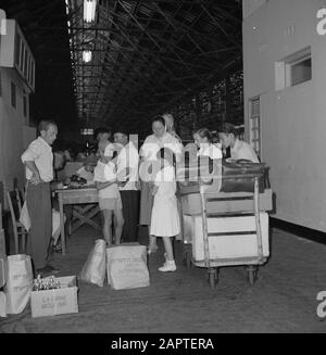 Israel 1964-1965: Haifa, Ankunft der Passagierschiffe; Zollgruppe der Reisenden mit einem Wagen voller Gepäck, der in einer Halle im Zollgebiet wartet Anmerkung: Haifa ist eine Hafenstadt und Badeort in Nordisraelisch, am nördlichen Teil des Karmelgebirges und am Mittelmeer. 1945 startete ZIM Lines (Schiffahrtsgesellschaft) als Versender jüdischer Einwanderer in den neuen Staat Israel und wurde zu einer der weltweit größten Schiffahrtsunternehmen mit Niederlassungen weltweit Datum: 1964 Standort: Haifa, Israel Schlagwörter: Gepäck, Zoll, Häfen, Piloten, Reisende Stockfoto