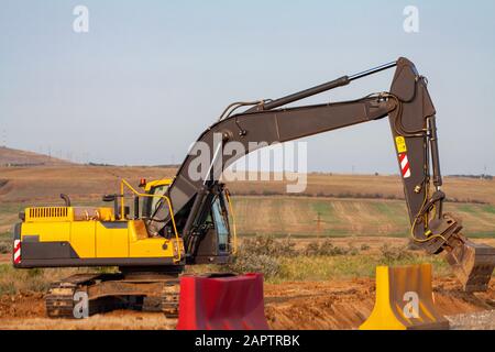 Einem großen eisernen Baggerschaufel sammelt und schüttet Sand Geröll und Steinen in einem Steinbruch auf der Baustelle Straße Einrichtungen und Häuser Stockfoto