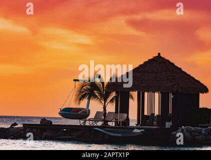 Flamingo Beach, Renaissance Island Aruba. Bamboo Strandbungalow mit Schaukel bei Sonnenuntergang. Stockfoto