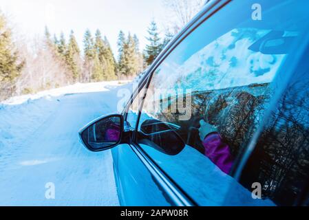 Blick auf den Rückspiegel eines fahrenden Autos auf einer schneebedeckten, winterlichen Oberfläche. Konzept des sicheren Fahrens im Winter Stockfoto