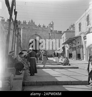 Israel 1948-1949 Jerusalem, Damaszener Tor mit Geschäften, einem shoeshine und einem wandelenden und sitzenden Publikum Datum: 1948 Ort: Damaskus, Israel, Jerusalem Schlüsselwörter: Architektur, Öffentlichkeit, Schuhpolierer, Stadtmauern, Stadttore, Straßenstatuen, Treppen, Geschäfte Stockfoto