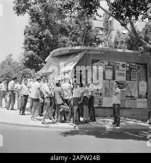 Israel 1964-1965: Tel Aviv, Karl Adolf Eichmann jüdische junge Männer mit Keppelts an einem Kiosk, der Zeitungen mit Nachrichten über den Fall Adolf Eichmann Vertrieb Anmerkung: Otto Adolf Eichmann (1906-1962) war ein deutscher SS-Funktionär im Dritten Reich und einer der Hauptverantwortlichen für den Massenmord an den Juden Datum: 1964 Standort: Israel, Tel Aviv Schlüsselwörter: Plakate, Jungen, jüdische Religion, Kioske, Zeitungen, Männer, Straßenbilder Personenname: Eichmann, Adolf: Umfrage, Willem van de, Stockfoto