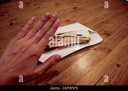 Ein Umschlag auf einem Holztisch. Steuern und Bestechungskonzept. Stockfoto