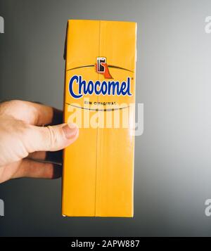 Paris, Frankreich - 27. Dezember 2019: Man Hand hält gelbe Packung Chocomel Schokoladengetränk vor grauem Hintergrund Stockfoto