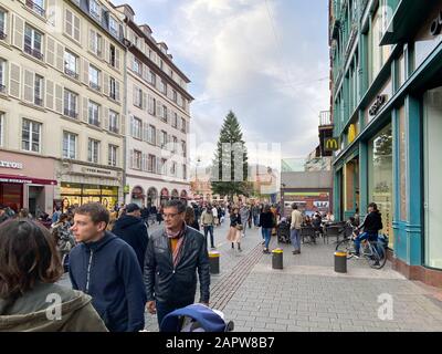 Paris, Frankreich - 02. November 2019: Fußgänger, die während des jährlichen Weihnachtsmarktes auf der Hauptstraße in Straßburg mit hohen Tannenbäumen im Hintergrund laufen Stockfoto