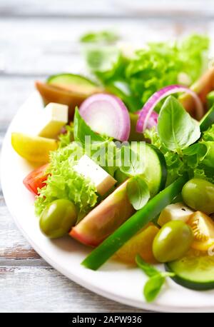 Gesunder Salat mit Fetakäse, grünen Oliven, Gurken, roter Zwiebel, grünem Pfeffer, verschiedenen Tomaten und frischem Basilikum. Nahaufnahme. Stockfoto